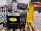 Assembled black conveyor head with motor, belt guard, drive, on a pallet, sitting inside a shop.